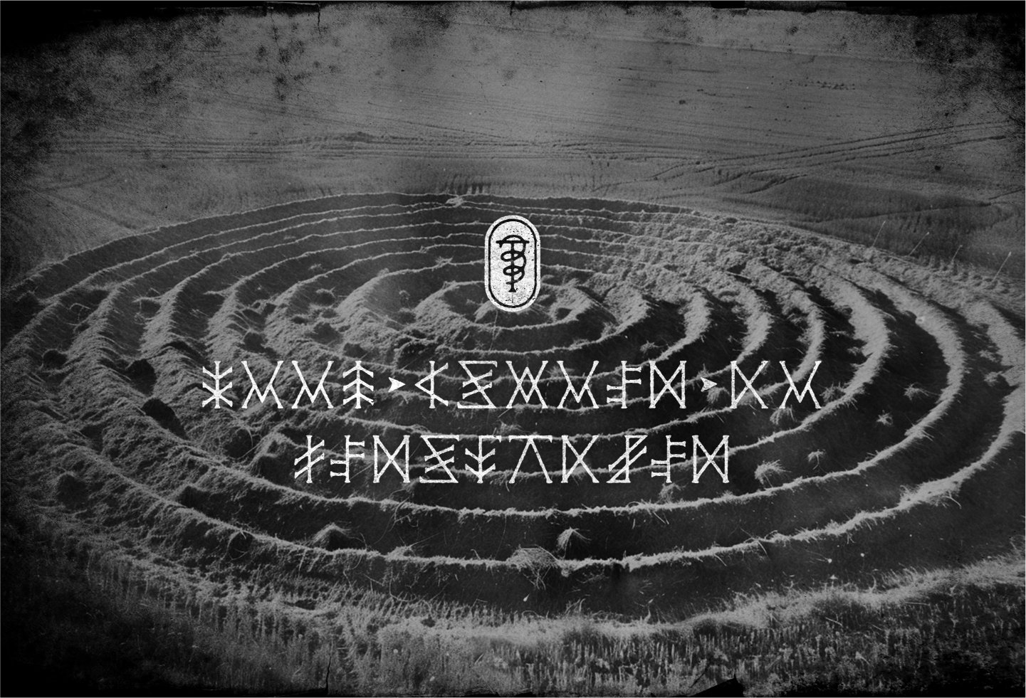 Black and white photo with film grain depicting a large crop circle in a field, overlaid with a white graphic glyph and message in coded alphabet.